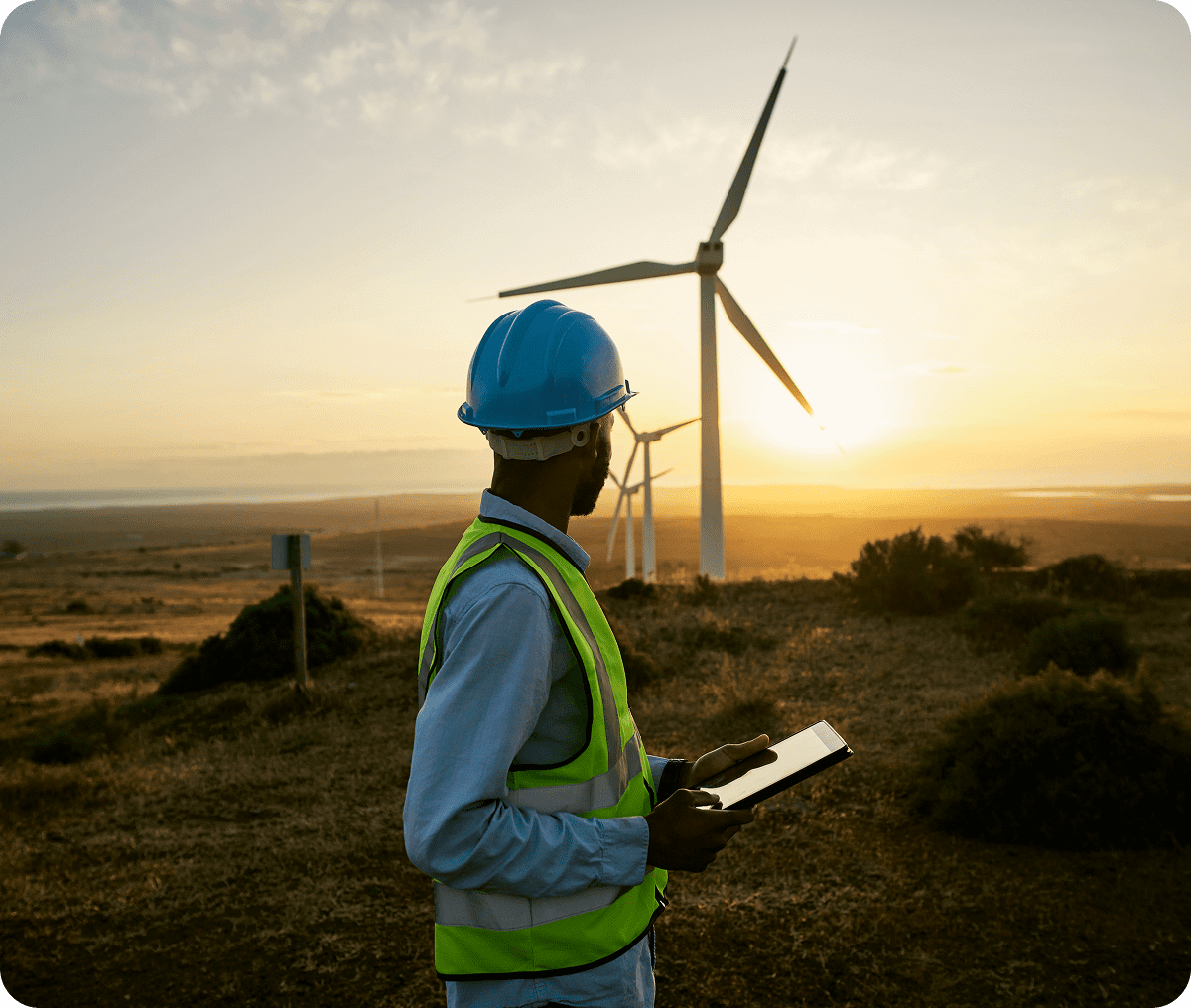 Engineer inspecting wind turbines at sunset